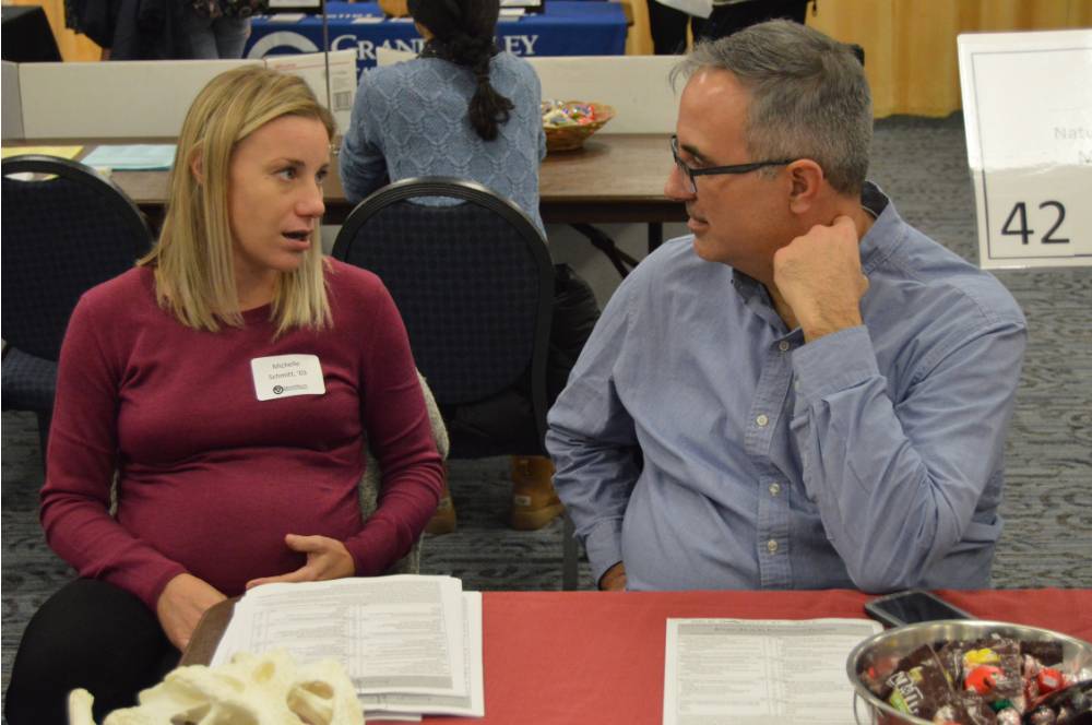 An alumna and a faculty member engage in conversation with one another at the Academic Major Fair.